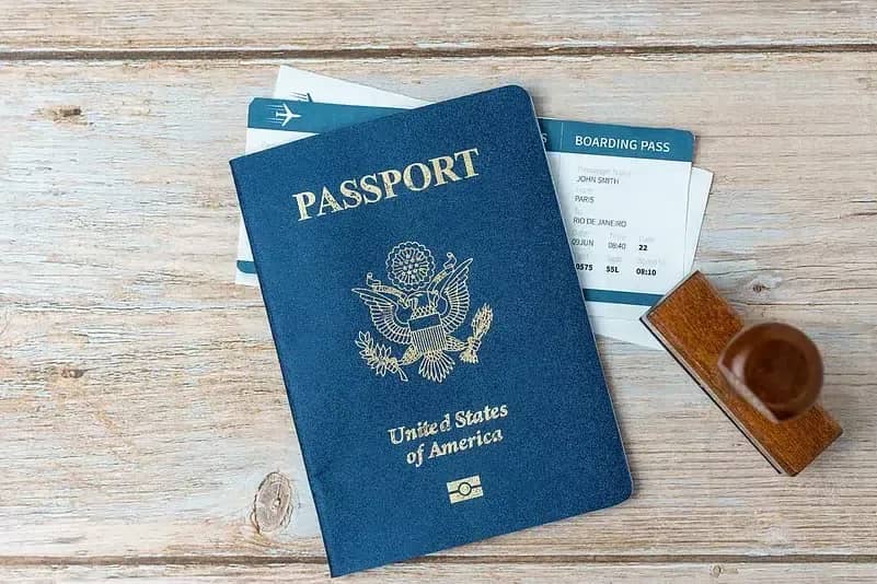 Pasaporte azul de Estados Unidos sobre una mesa de madera junto a una tarjeta de embarque y un sello