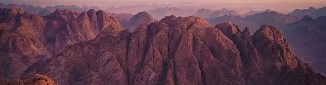 Jagged granite peaks of the Mount Sinai range in soft pink light
