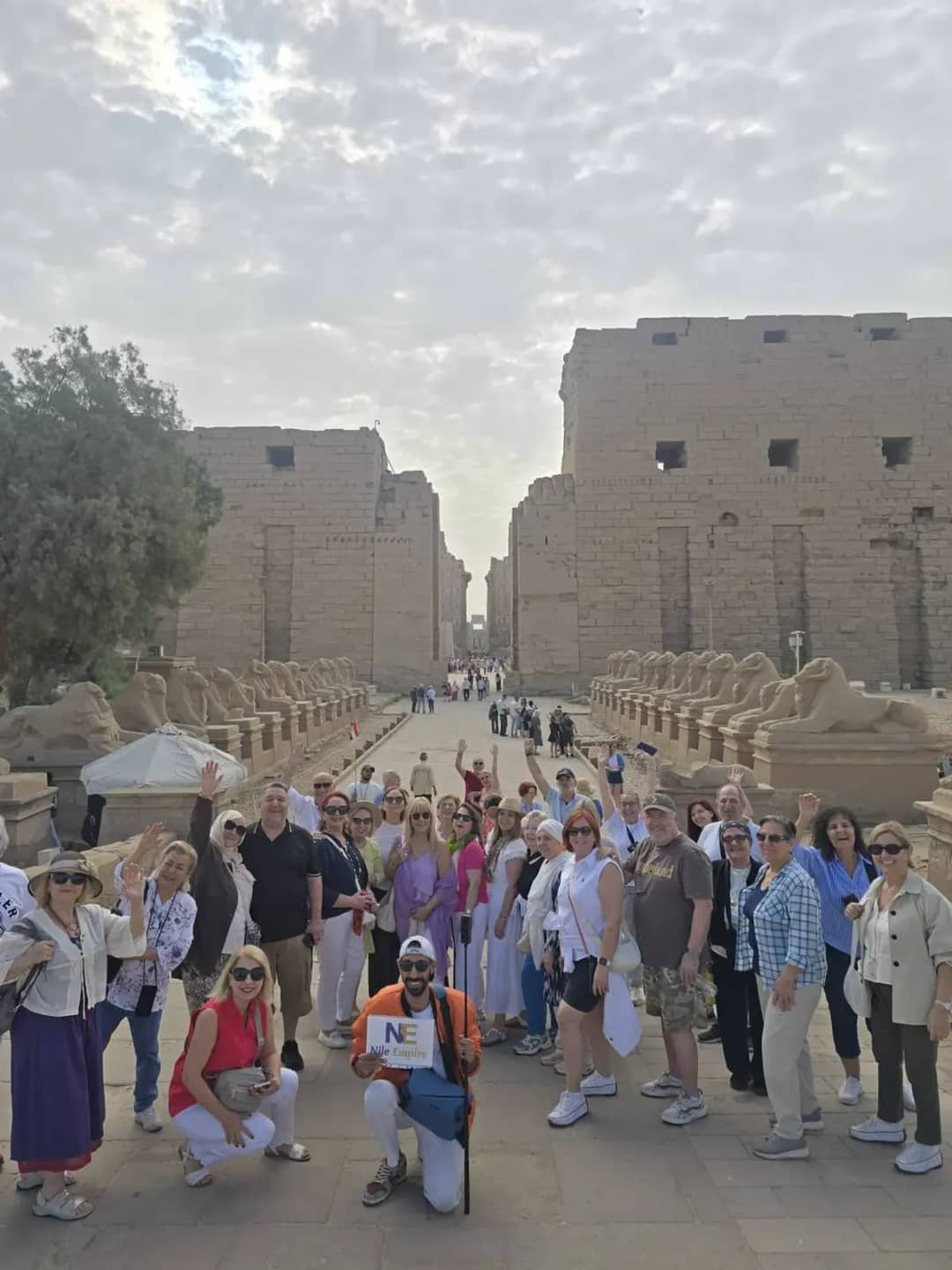 A group of travellers waving at the sphinx-lined entrance to Karnak Temple