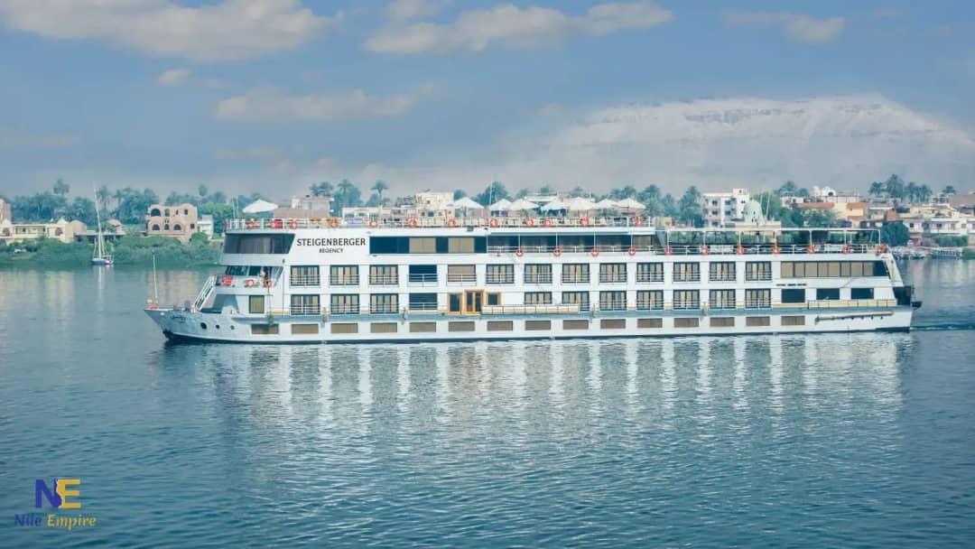 Crucero Steigenberger Regency navegando por el Nilo, con palmeras y casas en la orilla